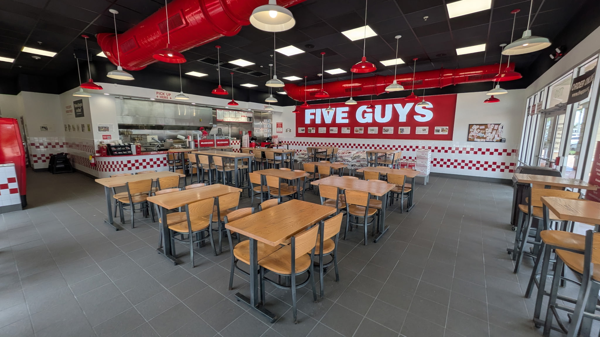 Image of the dining room of the Five Guys restaurant at 17819 Tamiami Trail in North Port, Florida. Photo shows tables, chairs and Five Guys signage.