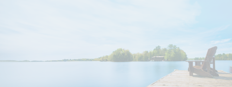 A red Muskoka chair on a dock overlooking a calm lake.