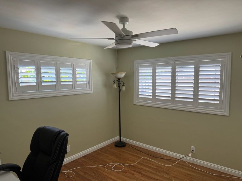 Custom white plantation shutters provide a crisp, clean finish to this home office. The classic louvers offer excellent light control and privacy, perfectly complementing the room's neutral and airy design.