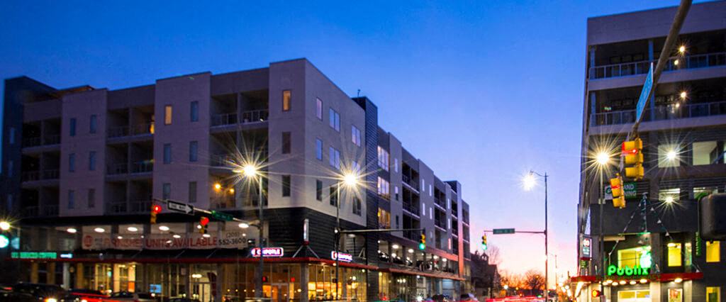 Mixed use development exterior at dusk with retail shops