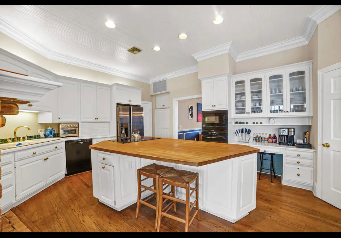 Before photo of a traditional kitchen remodel in Central Florida featuring white cabinetry, hardwood floors, and a center island, showcasing the starting point of a custom home renovation project.