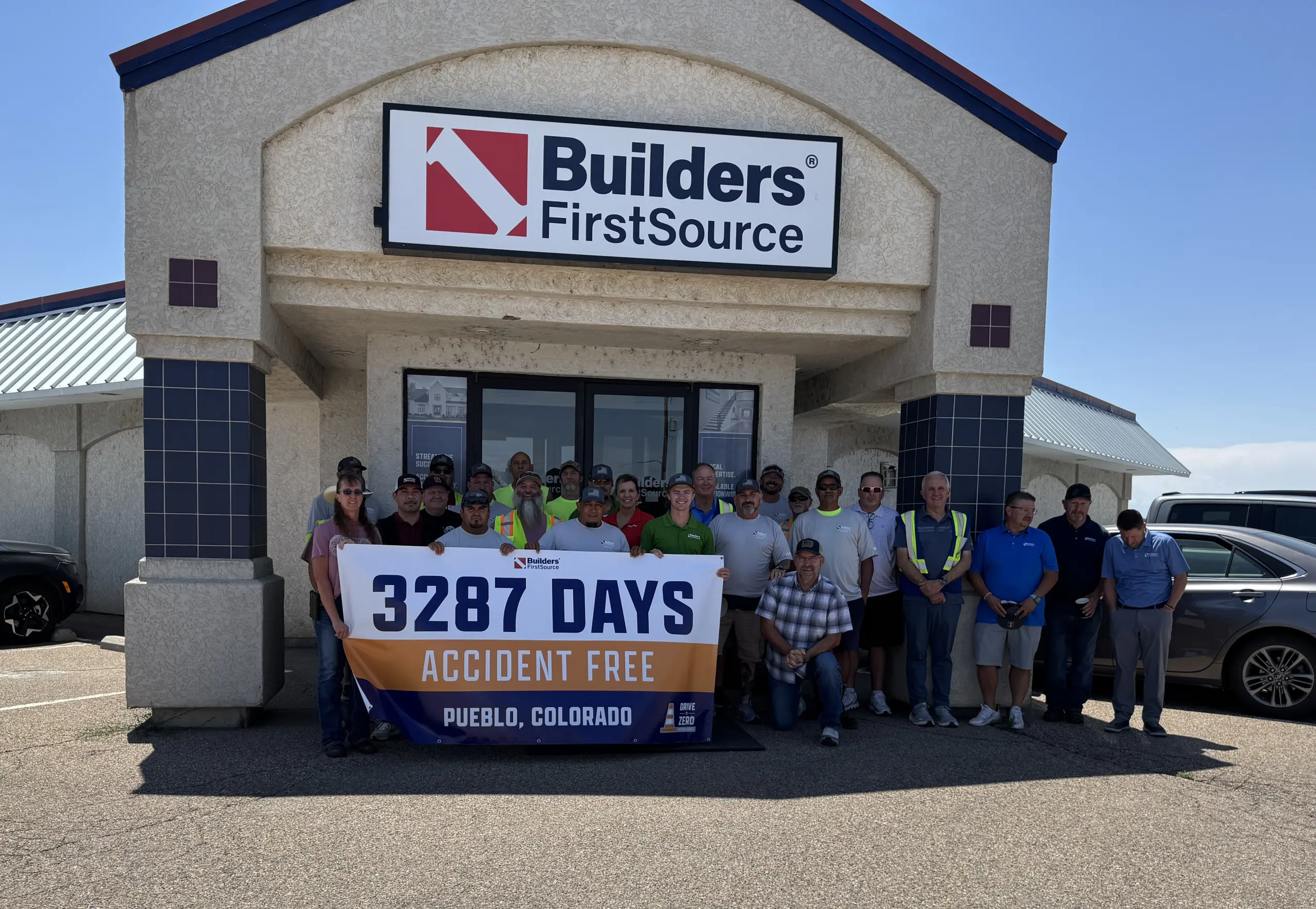Team members gathered outside a Builders FirstSource location in Pueblo, Colorado, holding a banner  