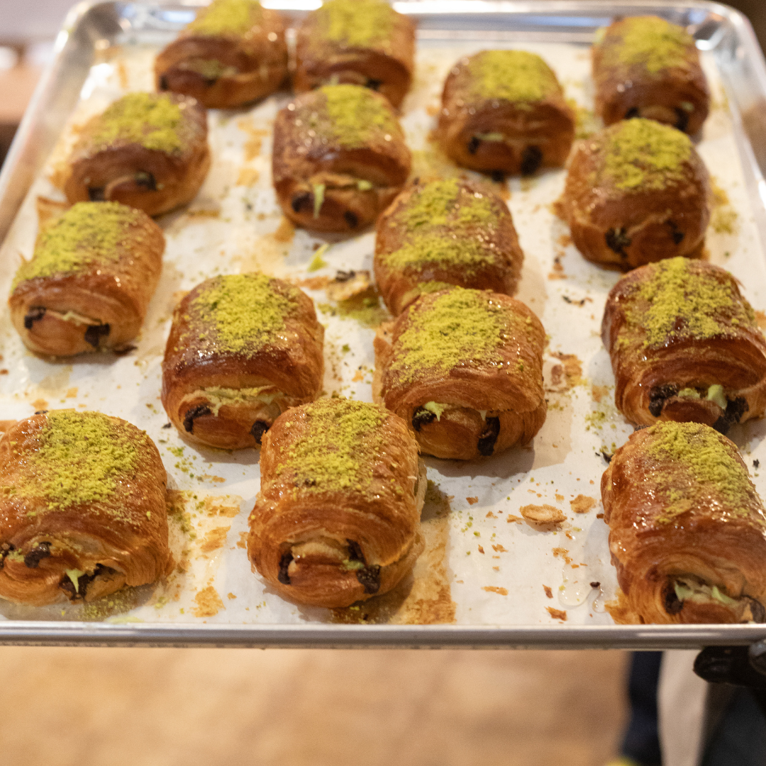 The image features a metal tray filled with freshly baked pastries arranged neatly in rows. Each pas 
