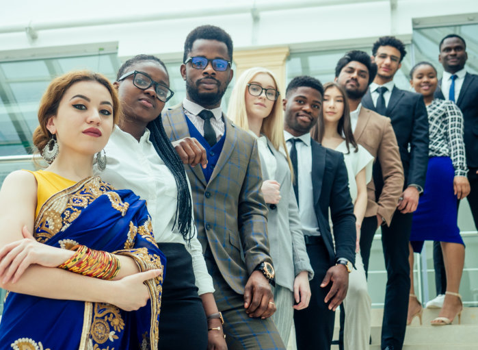 A diverse group of business professionals stands in a line, looking towards the camera. The individu 