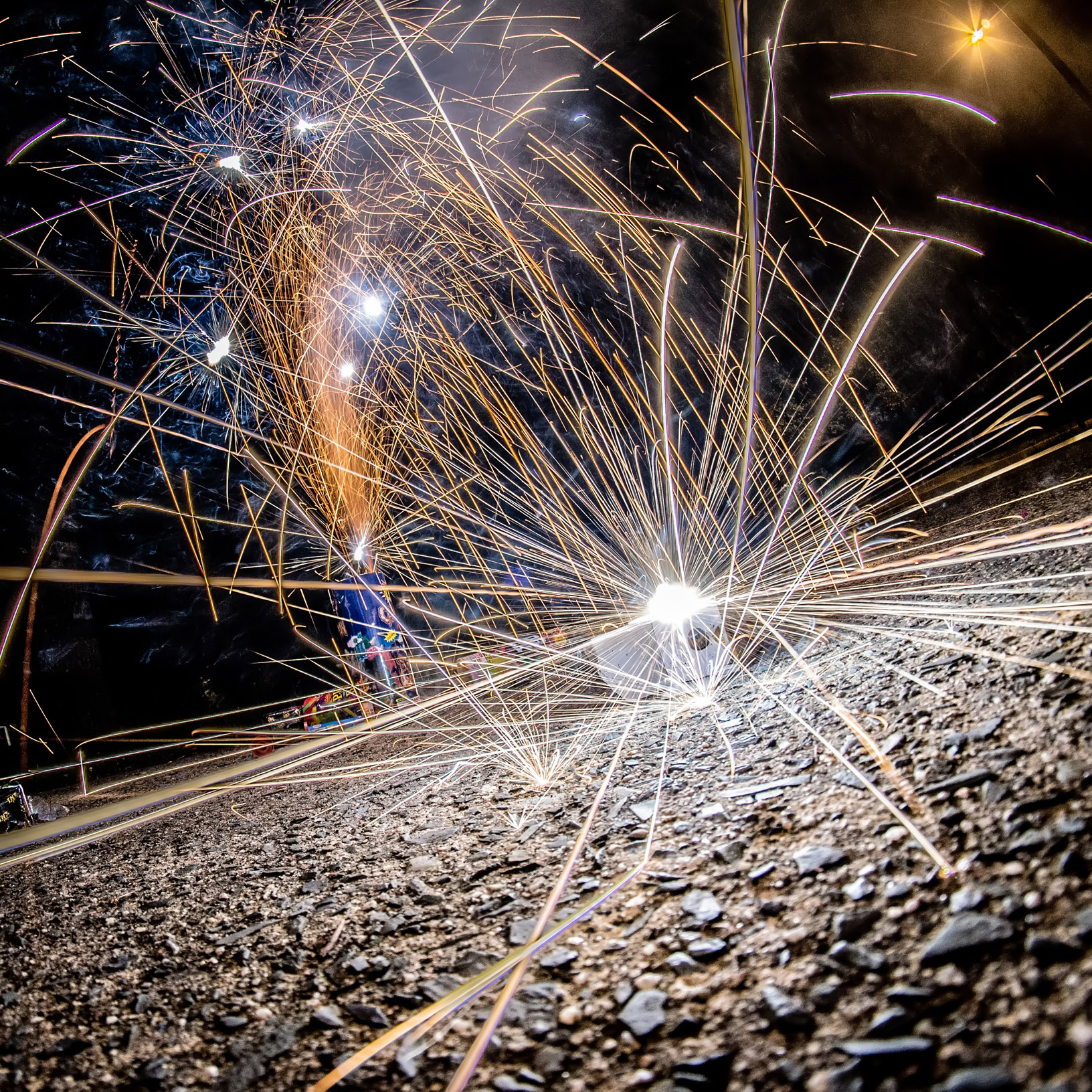 A picture of a few fireworks going off on a driveway.