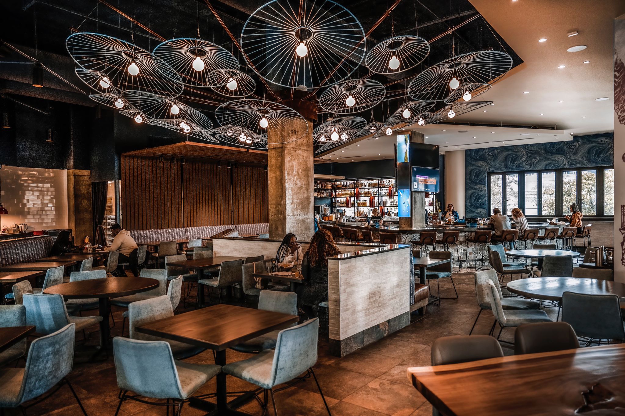 The space is open and airy, with a mix of seating arrangements to accommodate various group sizes. The decor blends modern and traditional Mexican-inspired elements, creating a stylish and welcoming ambiance.