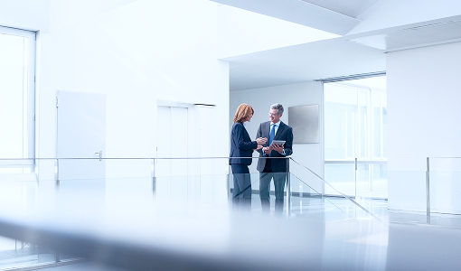 Two people standing in an office hallway.