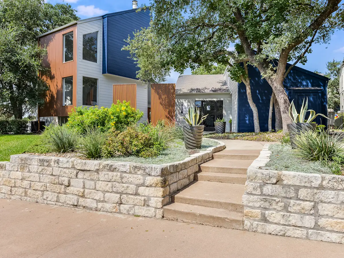 a stone retaining wall in front of a house with stairs