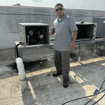 HVAC technician servicing rooftop commercial air conditioning units during maintenance inspection.