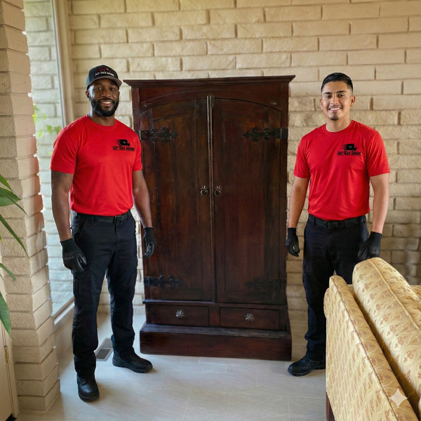 Two professional movers stand beside a large antique wooden cabinet after safely relocating it indoors, showcasing careful furniture handling, teamwork, and dependable residential moving services with customer satisfaction.