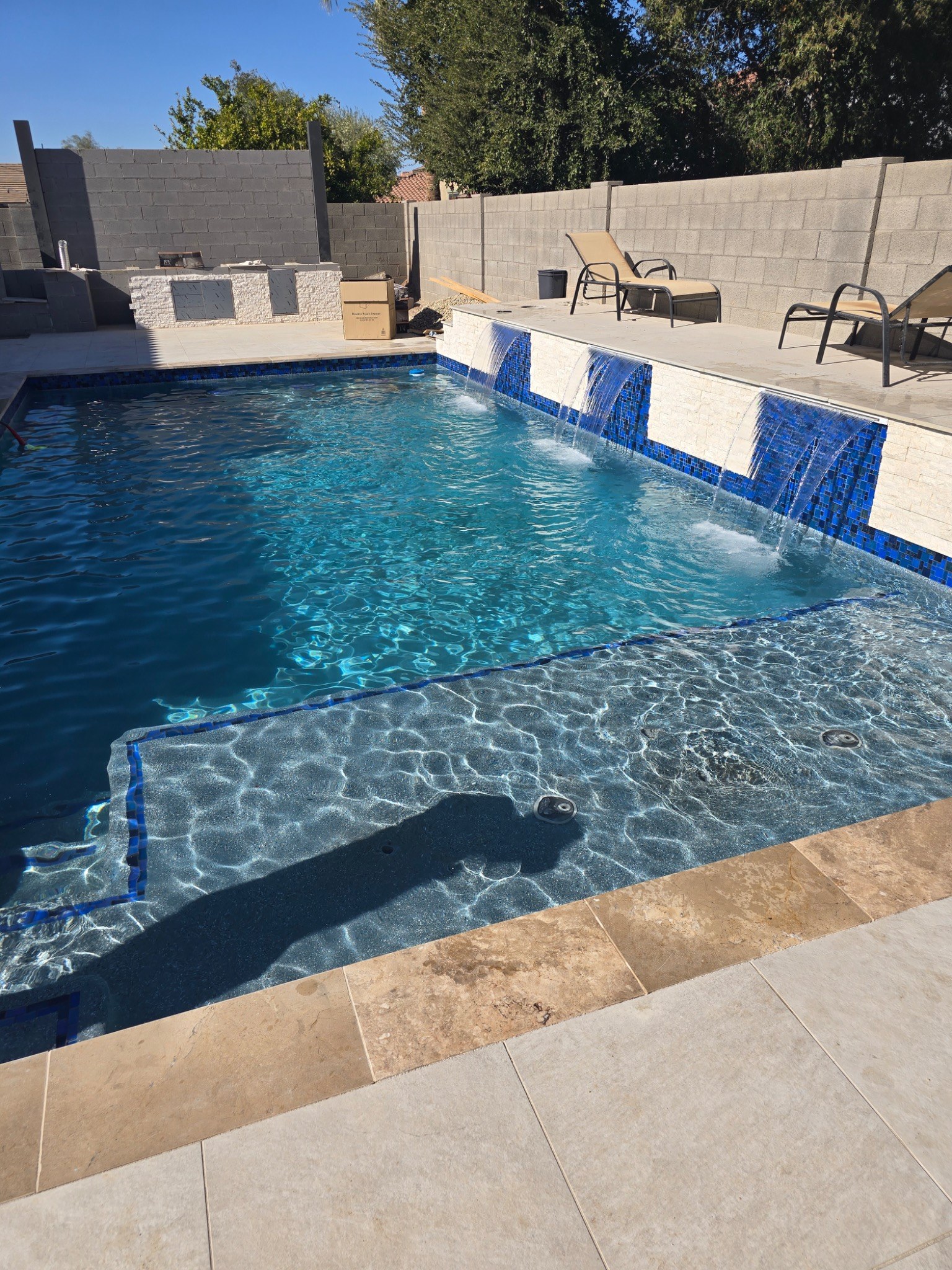 Water features can add movement, sound, and visual interest to a custom swimming pool. This backyard 