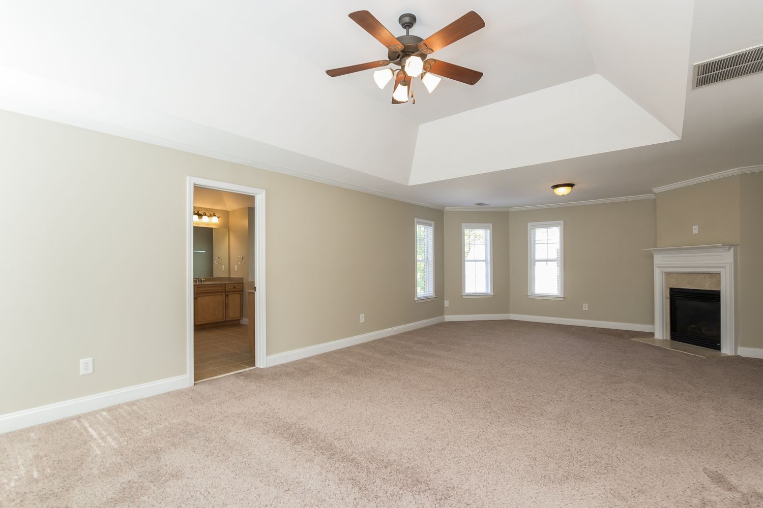 Spacious primary bedroom with adjoining bathroom and a cozy fireplace at Invitation Homes Atlanta.