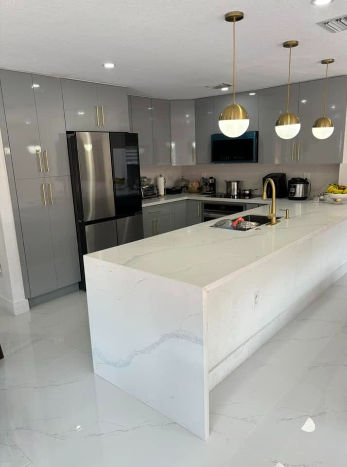 Remodelación de cocina moderna con isla en cascada de cuarzo calacatta, gabinetes grises de alto bri 