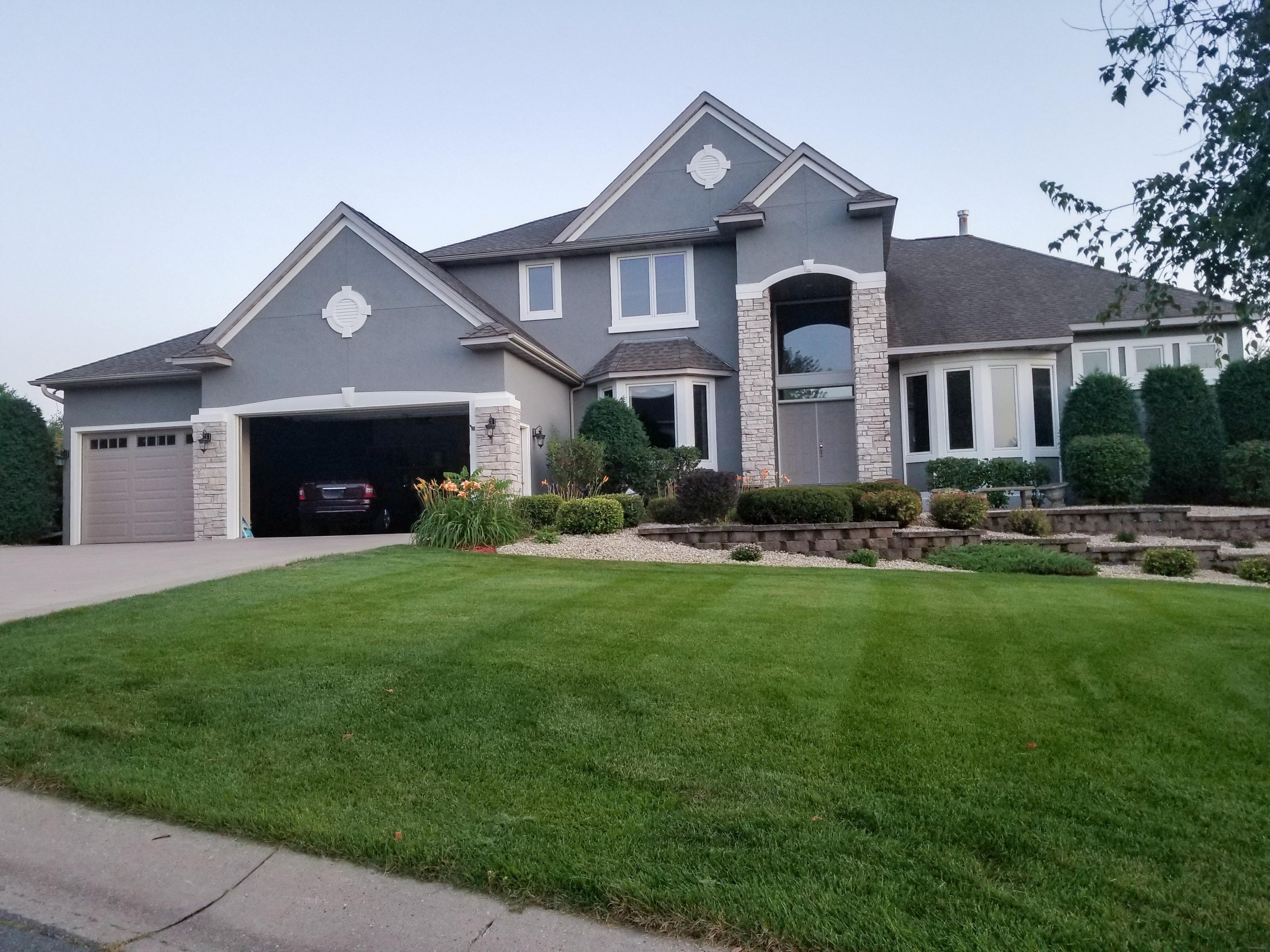 Custom seamless gutters installed on a large luxury grey and stone home by Ultimate Gutter Solutions.