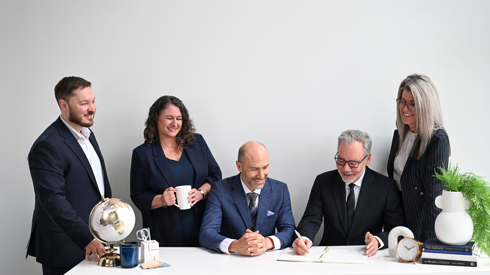 Photo of 5 employees looking over a piece of paper smiling.