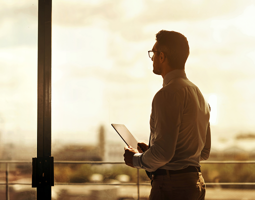 A professional looking out of an office window.