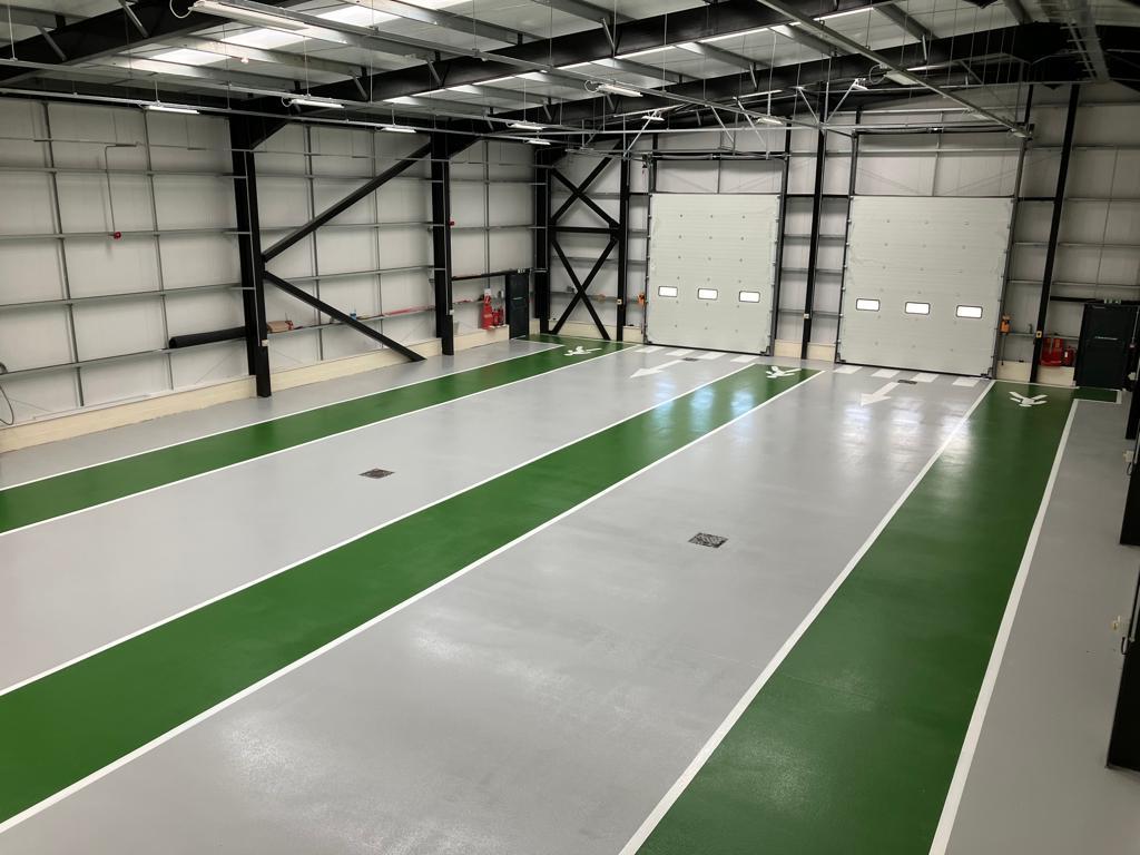 Grey resin floor with green gangways installed at a vehicle storage warehouse in Hull, UK Monarch Resin Floors Ltd Dronfield 01246 412222