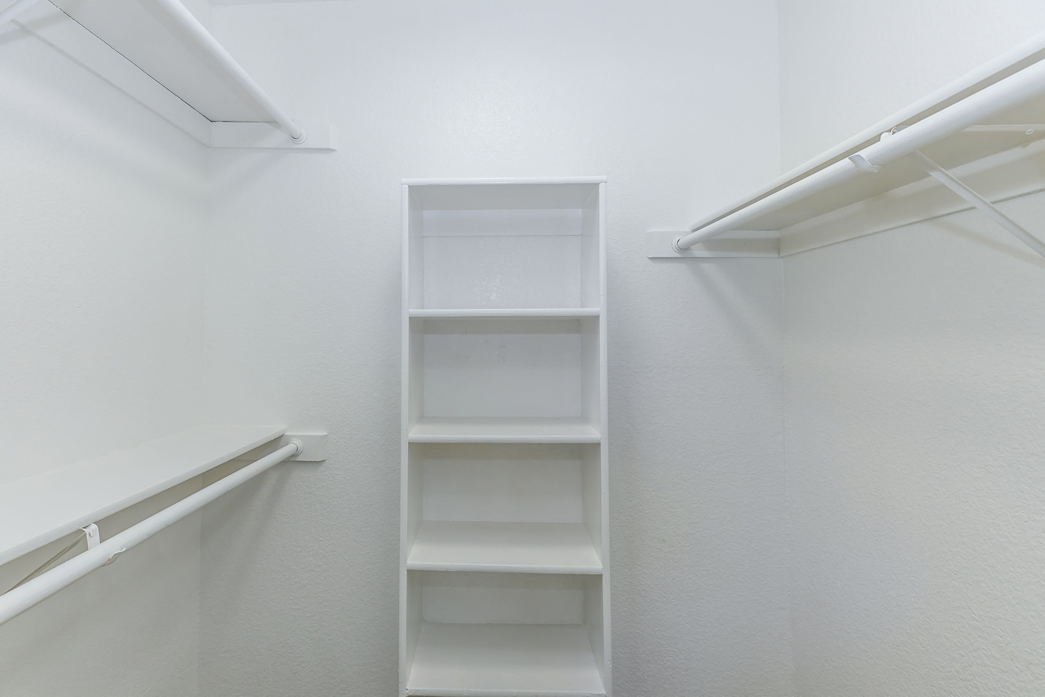 an empty closet in a room with white walls and shelves