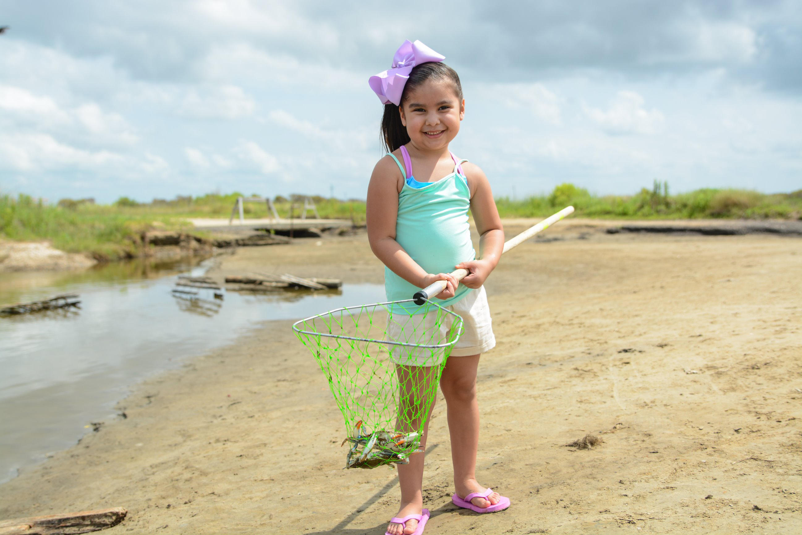 young girl enjoys crabbing at sea rim state park, holds up her crab in Port Arthur, Texas