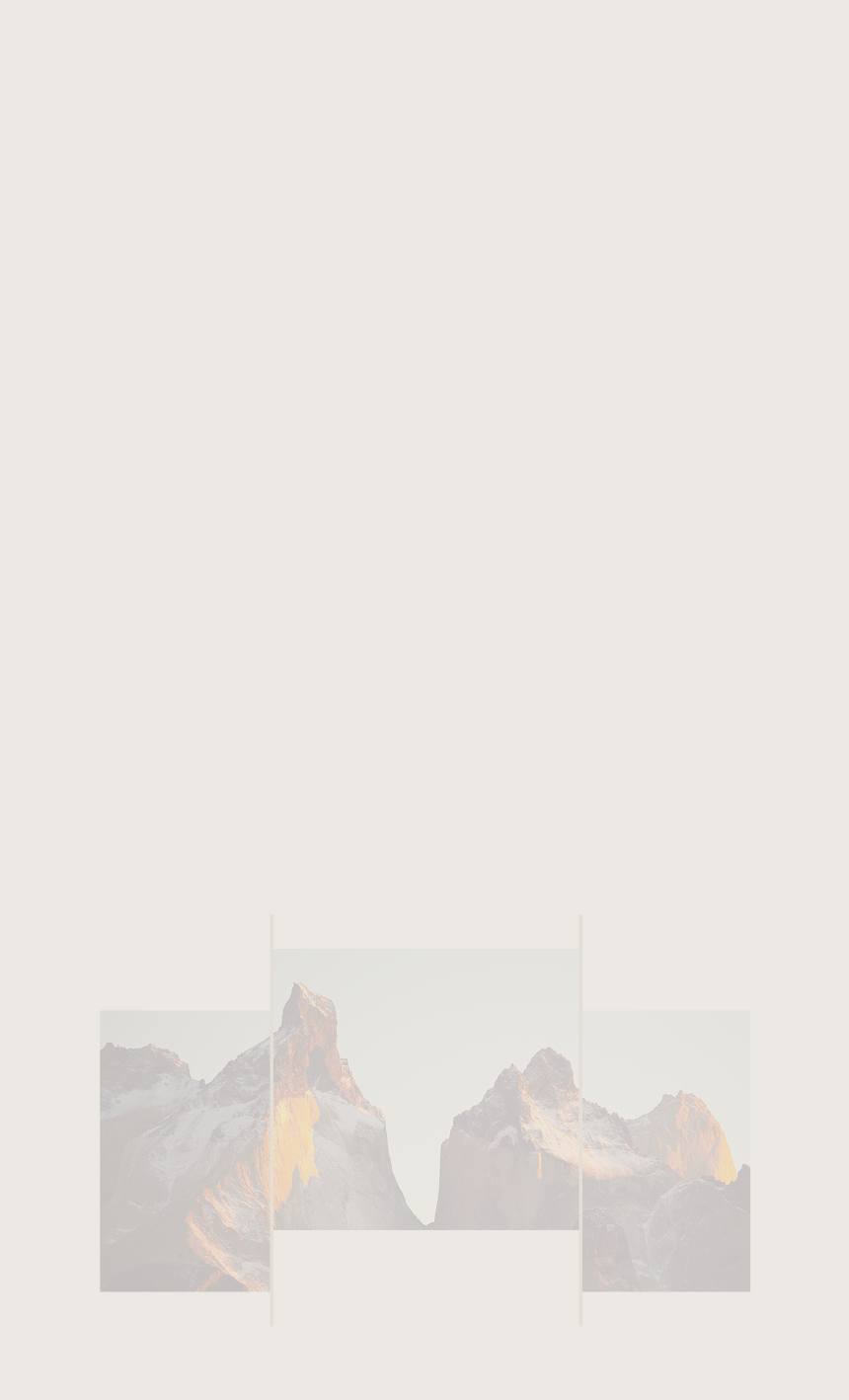Sun reflecting off the rockface on the side of a rugged, snow-capped mountain.