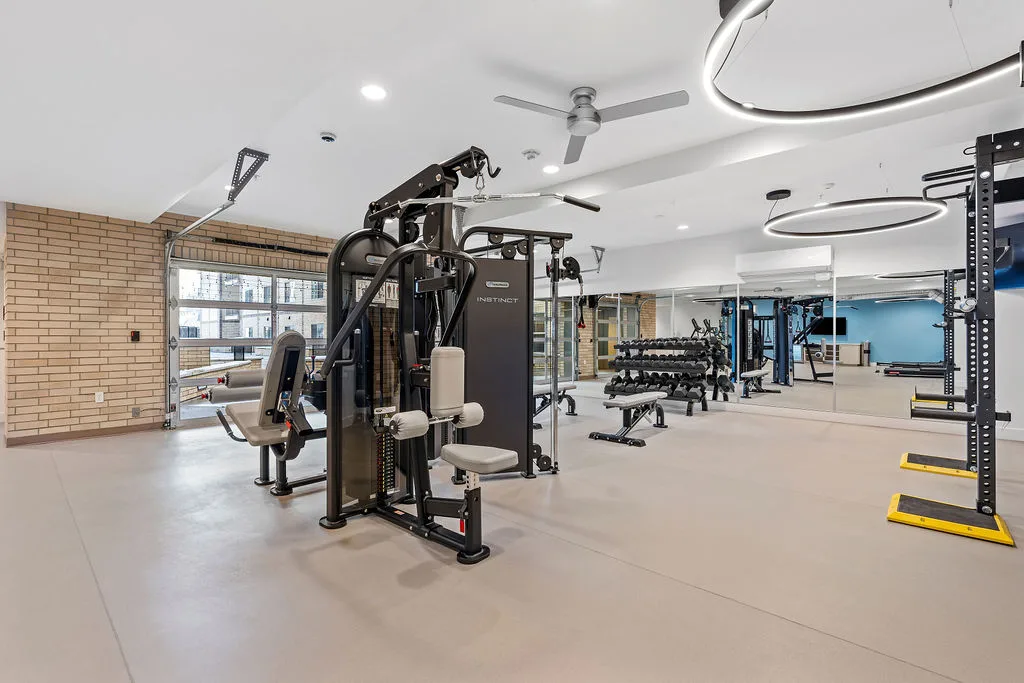 a gym with weights and cardio equipment and a ceiling fan
