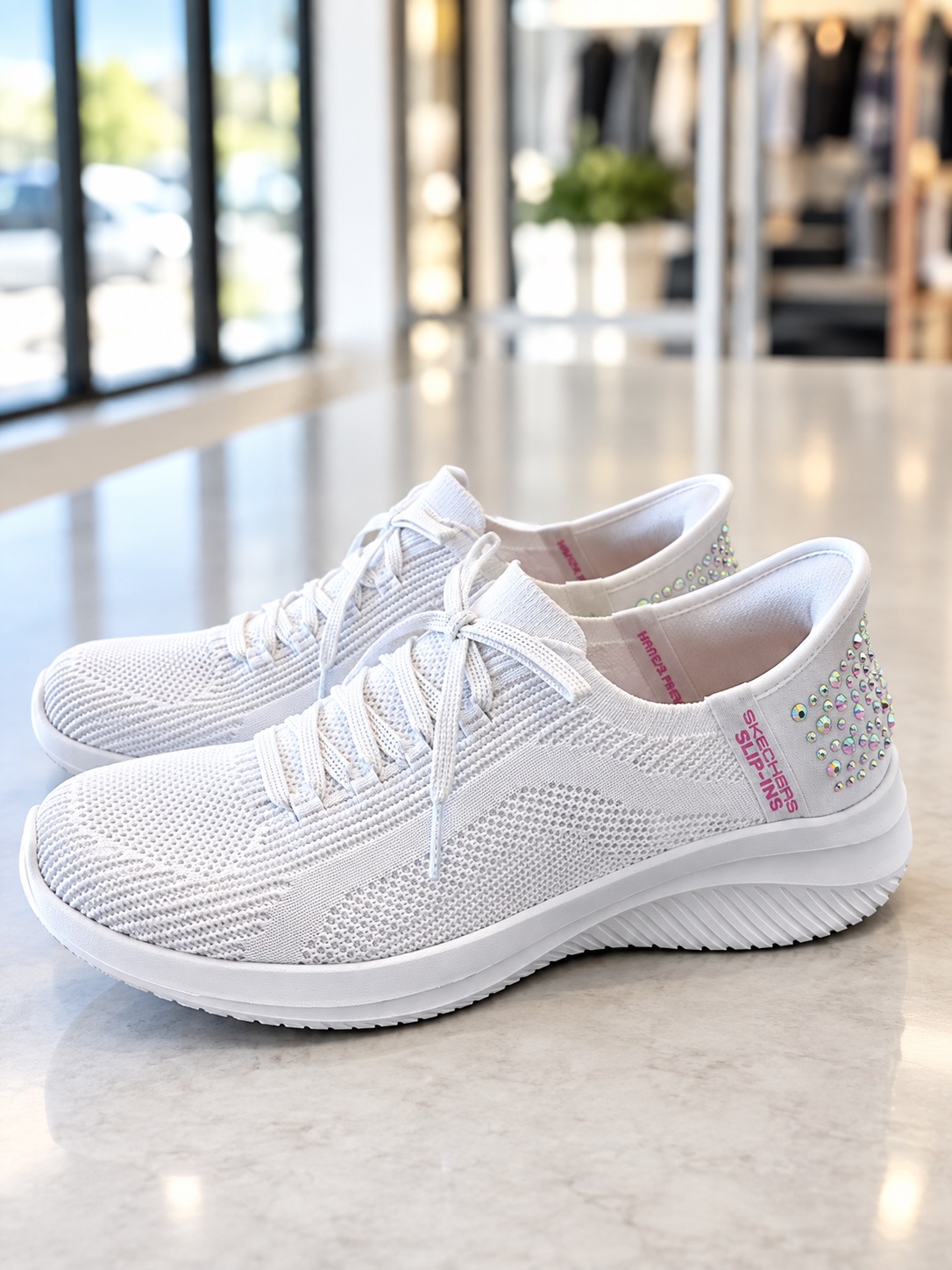 A pair of crisp, white rhinestone-accented slip-on sneakers meticulously cleaned and restored to like-new condition at Plaza Cleaners