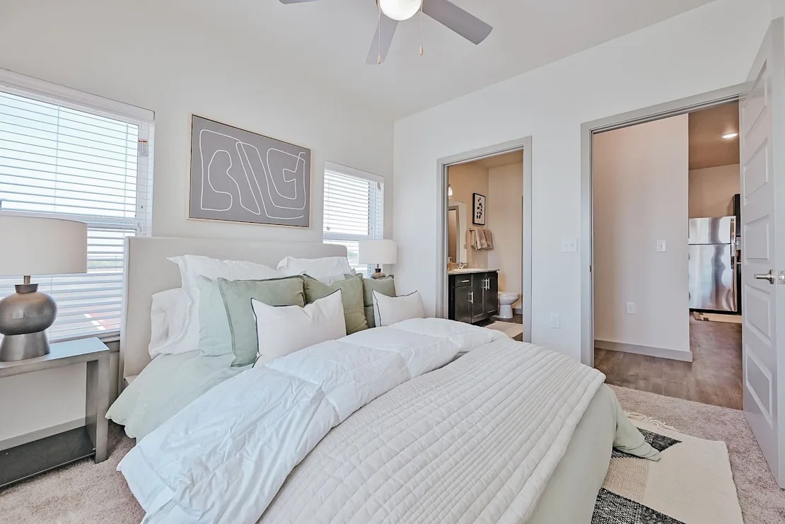 A bedroom with a large bed and a ceiling fan.