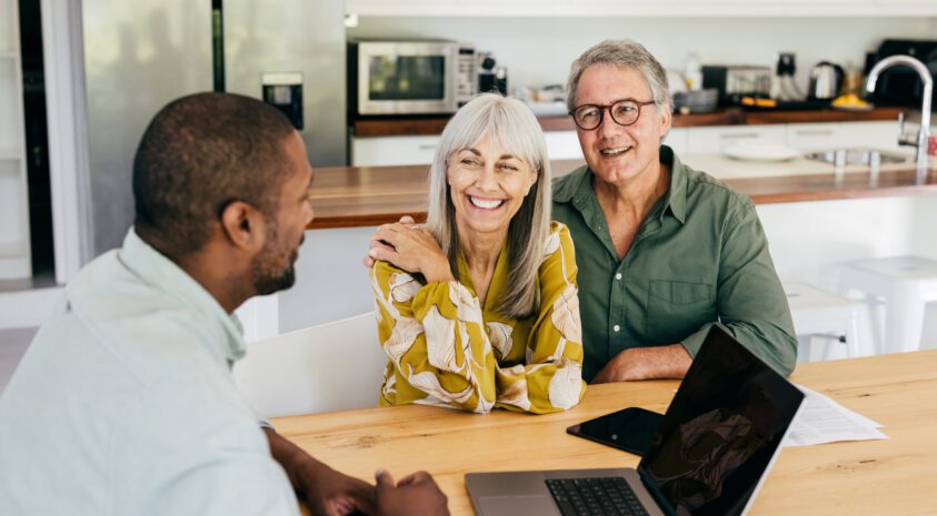 Older couple sits in their kitchen with a financial advisor.
