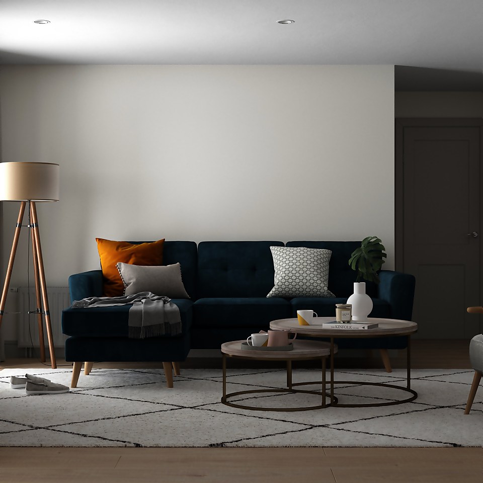 A white living room with a navy blue sofa and white rug.