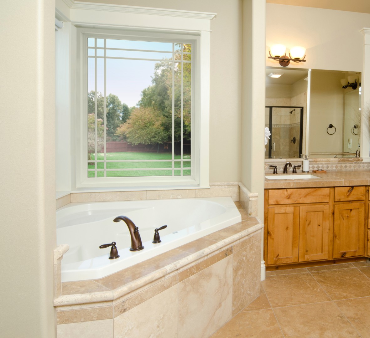 The EcoTek 1200 - 2200 Series Picture Window with Grids elevates this master bathroom with abundant natural light and a scenic outdoor view. The classic grid pattern adds an elegant touch, complementing the bathroom's modern fixtures and warm, neutral tones.