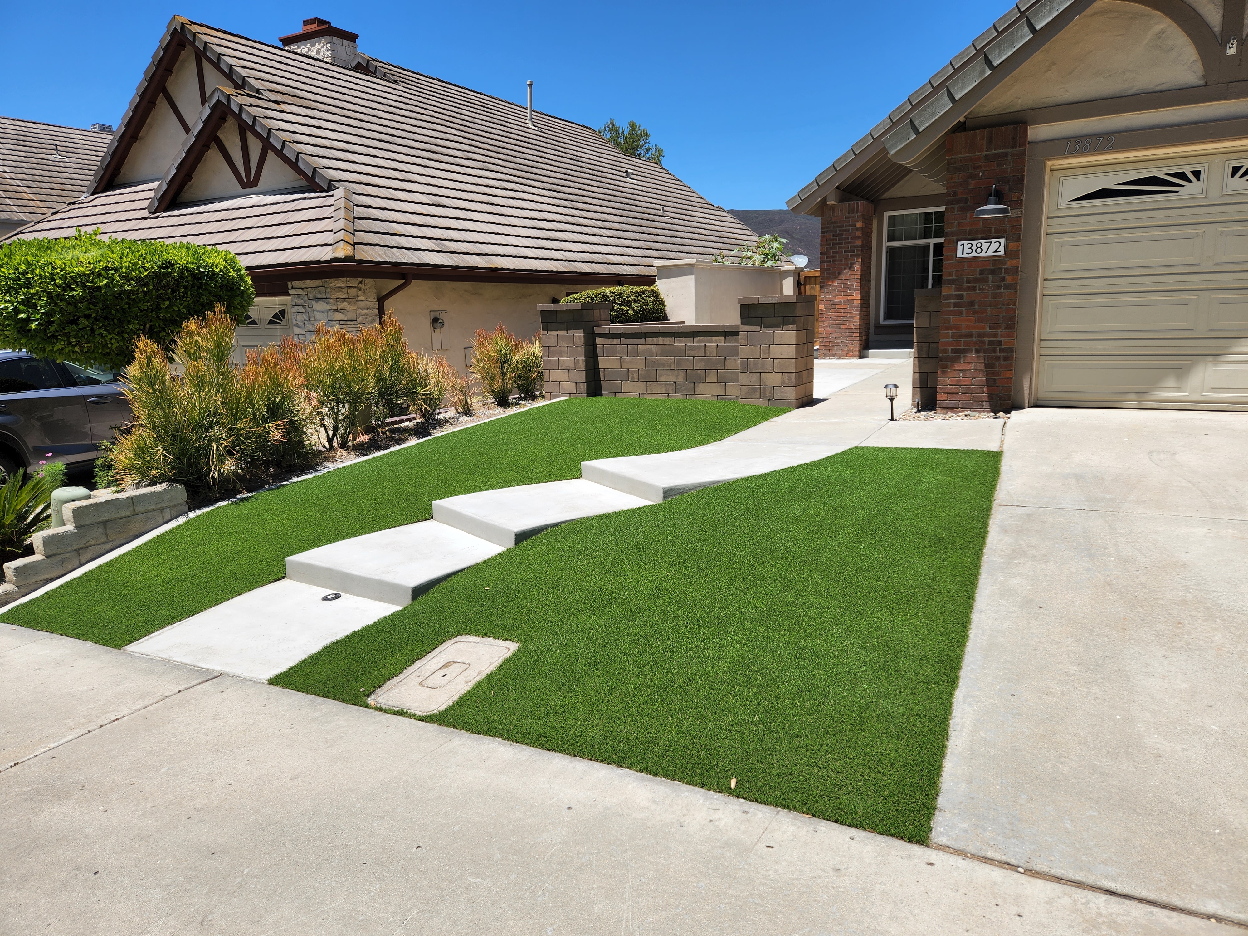 New front yard with contemporary mortarless walls, artificial turf and new concrete walkway/stairs.