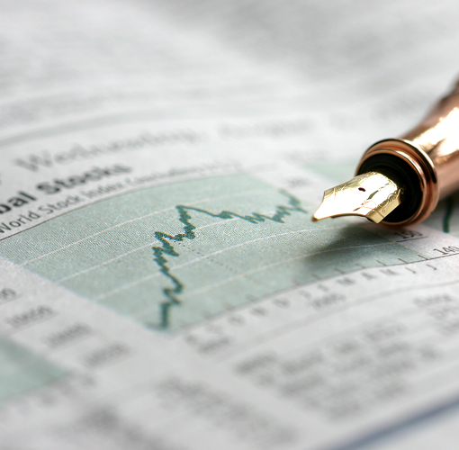 A close-up of a pen laying on stop of a printed stock chart.