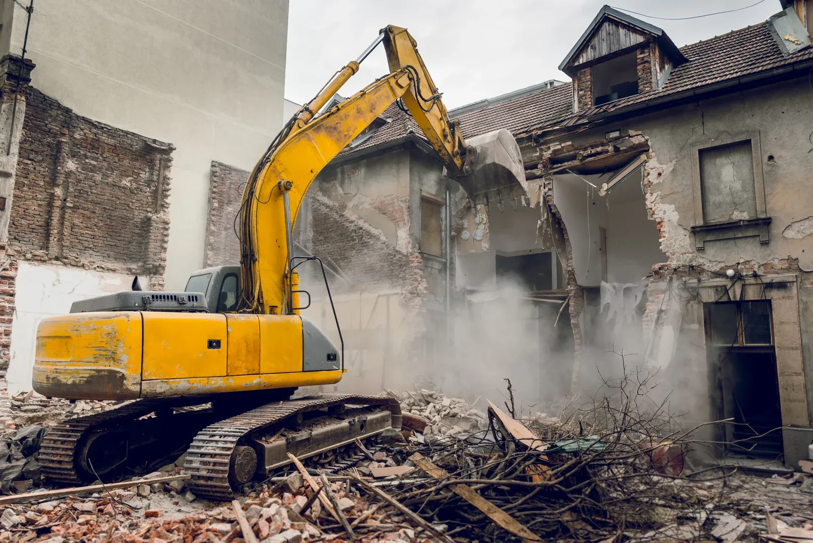 Excavator demolishing an old building, breaking down walls and structures for redevelopment. Heavy machinery efficiently clears debris, making way for new construction projects. Demolition services ensure safe, controlled removal of outdated or damaged structures.