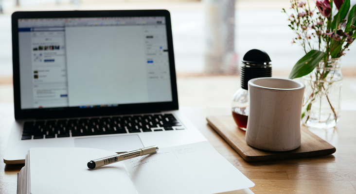 A laptop and coffee mug on a desk.