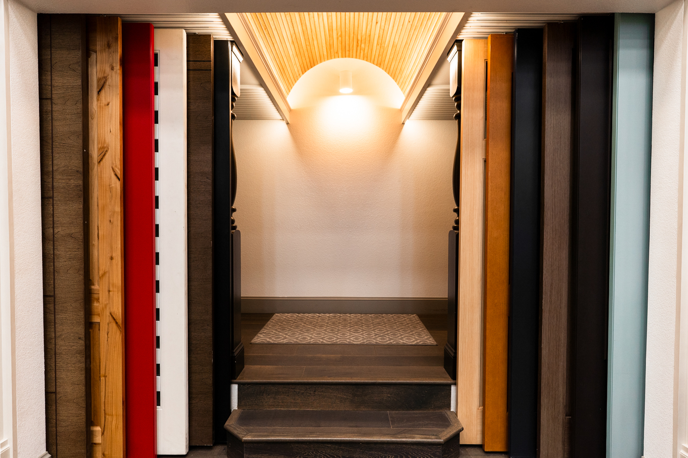 Builders FirstSource showroom with diverse wood panels, elegant lighting, and a cozy rug on dark steps, showcasing materials.