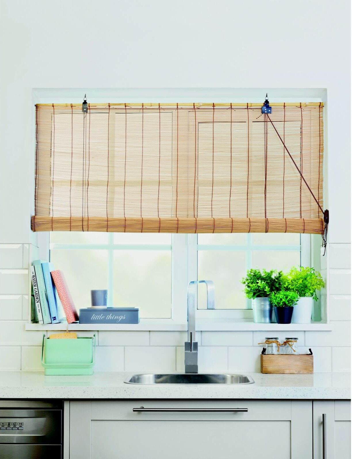 A bamboo window blind adorns a window behind a kitchen sink.