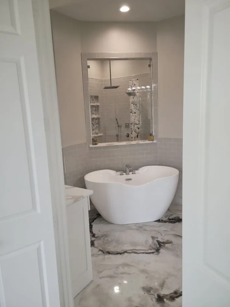 Spacious luxury bathroom features freestanding soaking tub, glass shower enclosure, polished flooring, and premium plumbing fixtures, demonstrating elegant residential bathroom remodeling with exceptional craftsmanship and modern interior design.