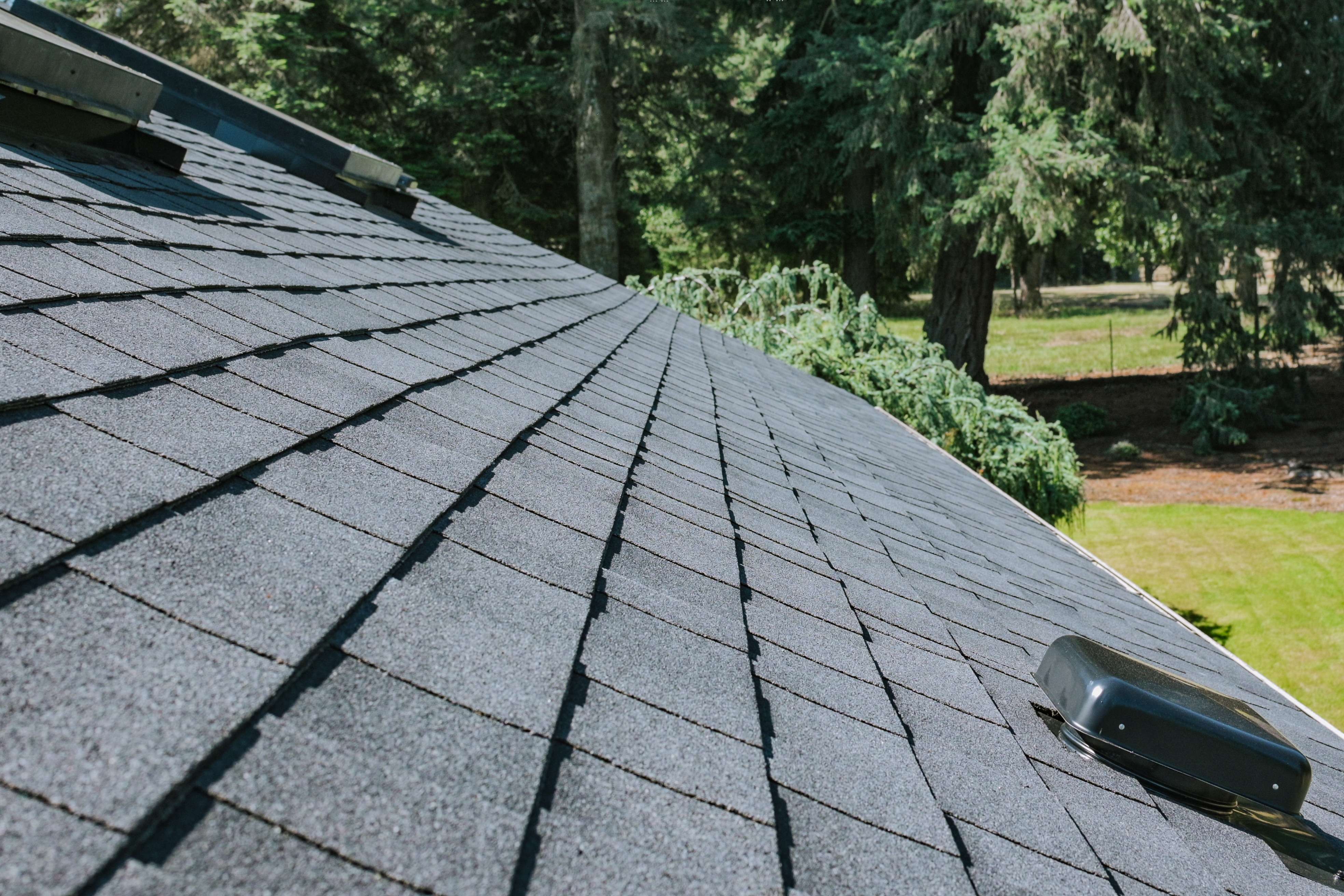 Residential asphalt shingle roof with multiple roof vents installed for attic ventilation. 