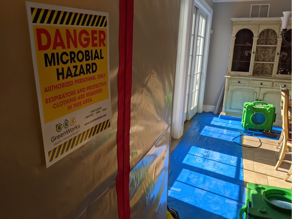 Mold remediation containment photo showing a sealed work area with clear communication and safety signage to protect occupants during cleanup.