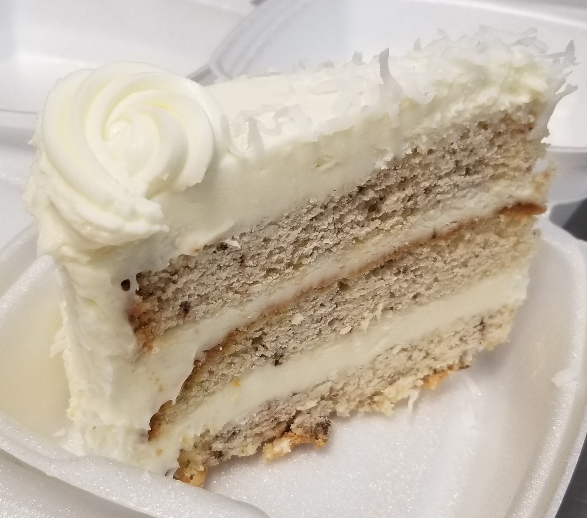 Smooth and delicious Italian Cream Cake. Vanilla buttercream cake with shaved coconut sprinkled on top with thick layers of buttercream icing inbetween and coated on top.