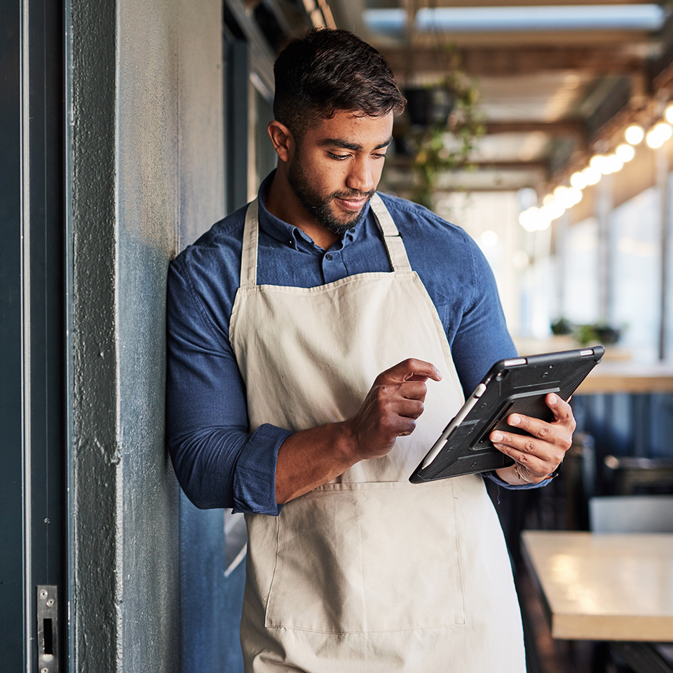 A man in an apron using a tablet.