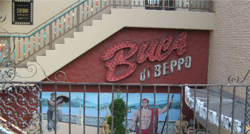 Buca di Beppo Kansas City showing a Buca sign on the side of a flight of stairs with a painted picture underneath.