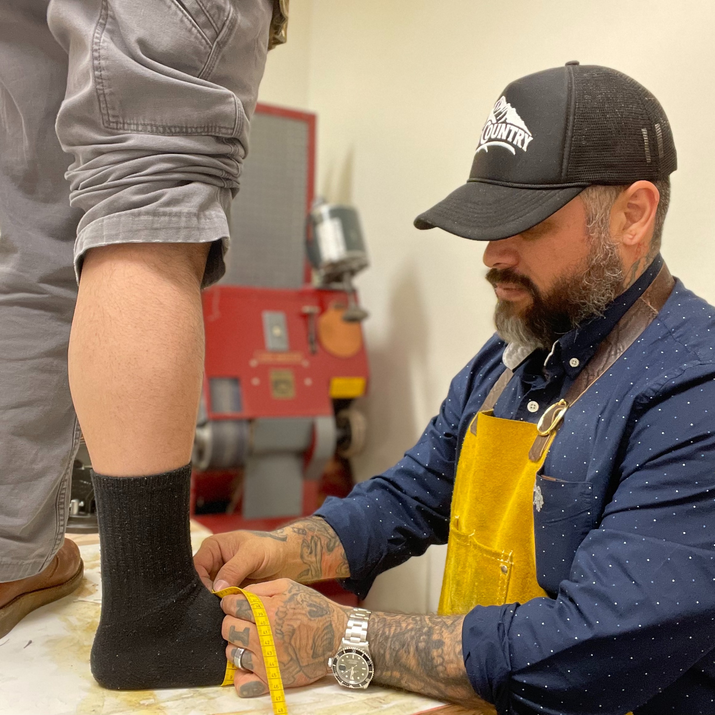 An Old Country bootmaker carefully measures a customer’s foot for a personalized cowboy boot fitting 