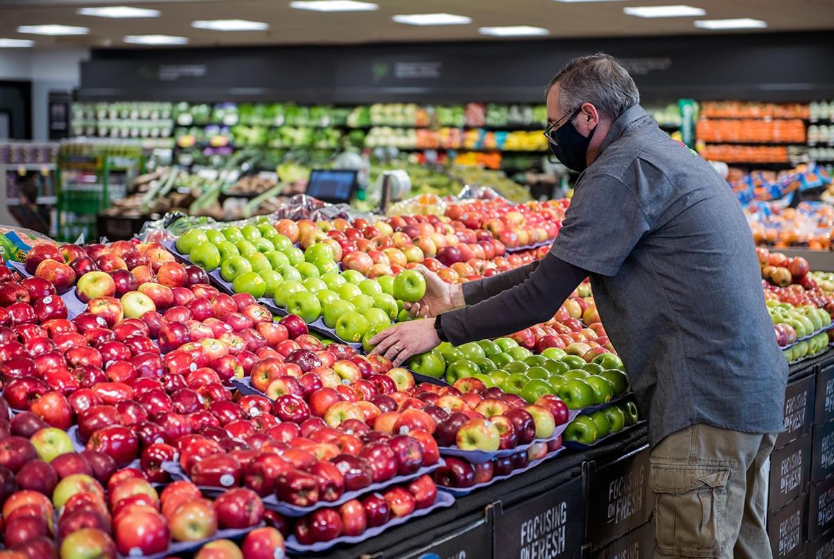 Wide shot of associate stocking fresh produce.