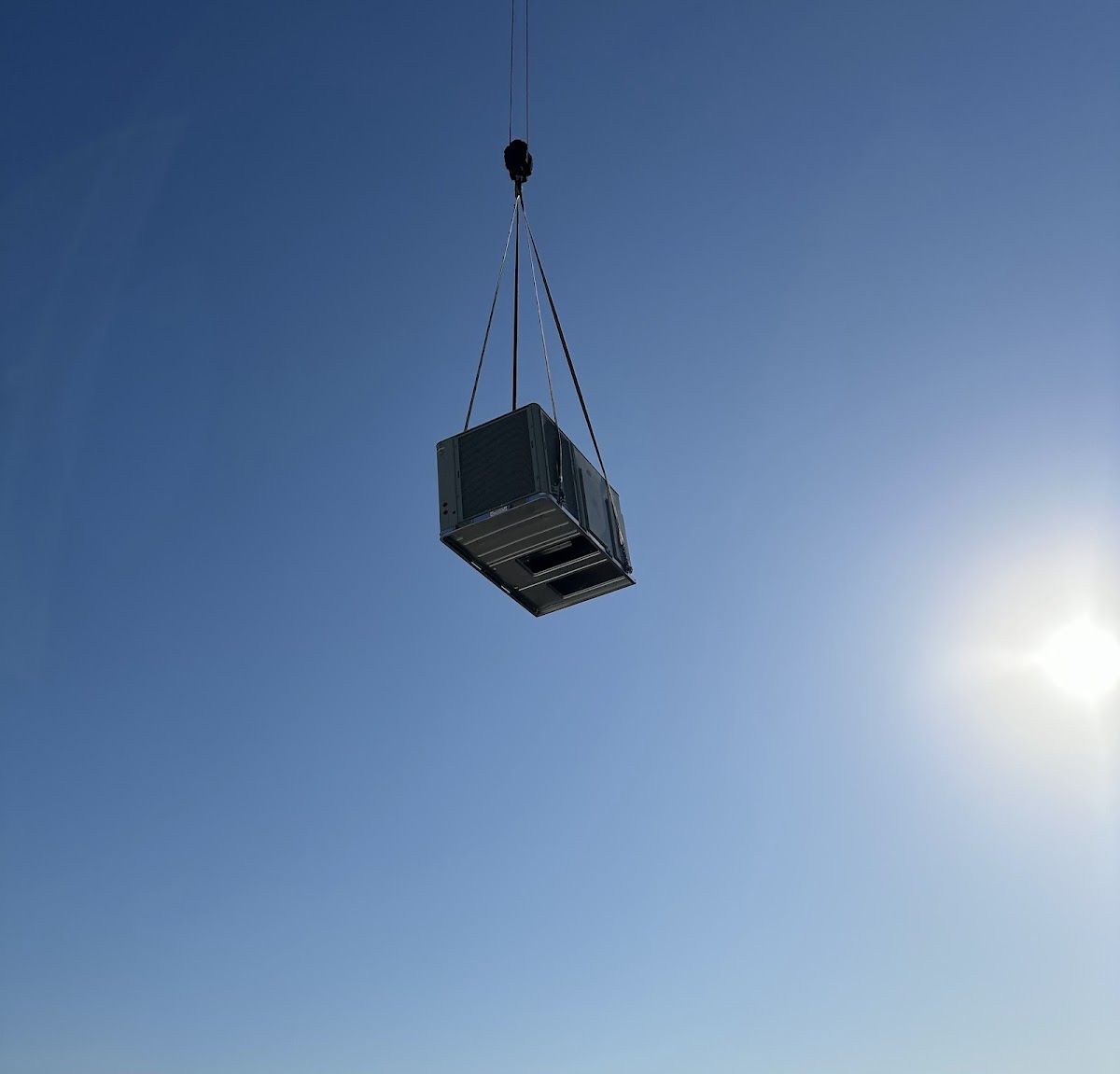 Commercial HVAC unit being lifted by crane for rooftop installation to support reliable heating, cooling, and airflow.
