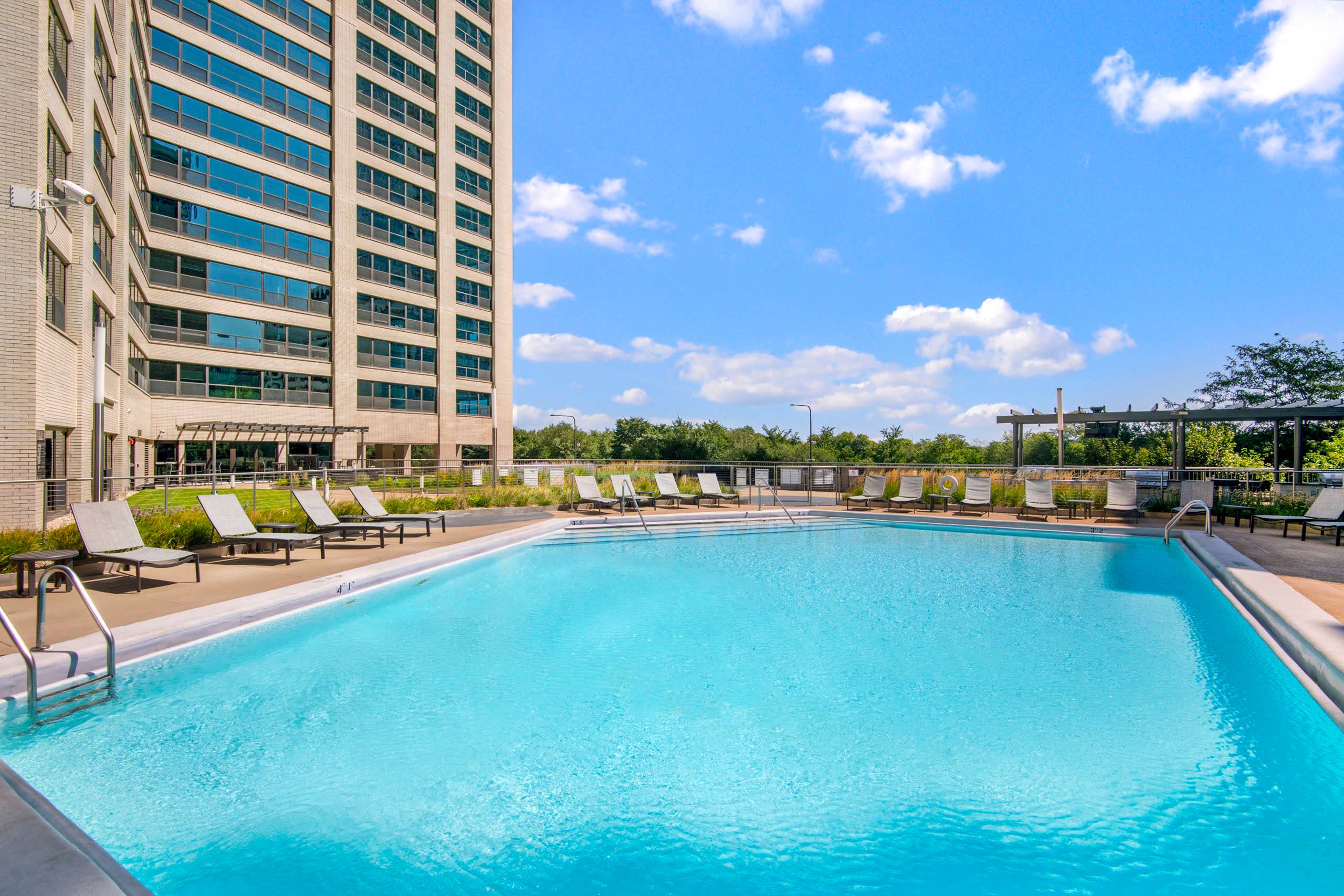 Rooftop pool with lounge chairs and skyline views 