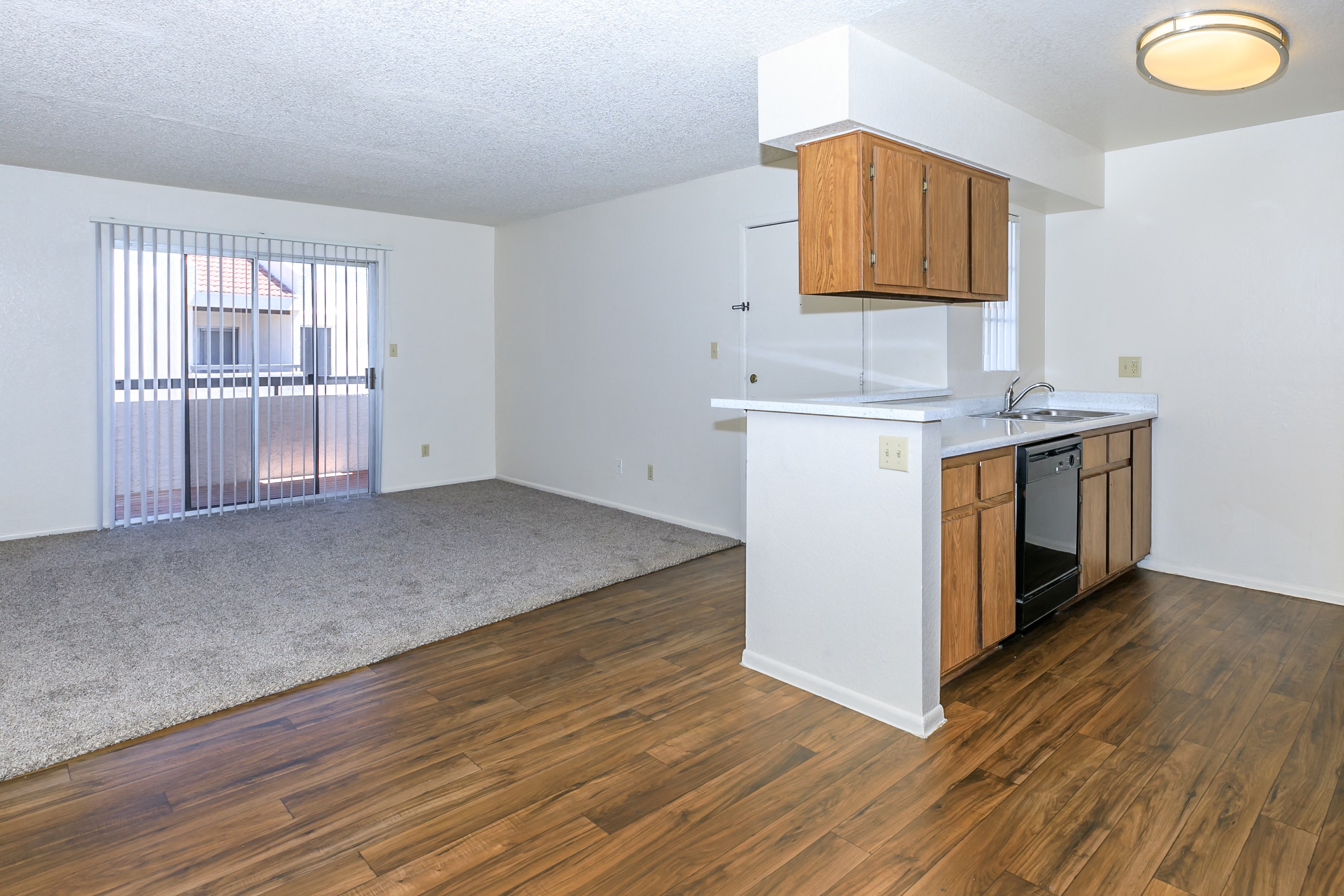 an empty kitchen and living room with wood flooring and a window