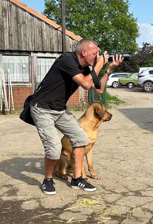Fotogebell Hundefotografie - Carsten Pöhler Fotograf erstellt Hundefoto auf Hofgelände, authentische Outdoor Hundefotografie Münster mit natürlicher Interaktion zwischen Mensch und Tier.