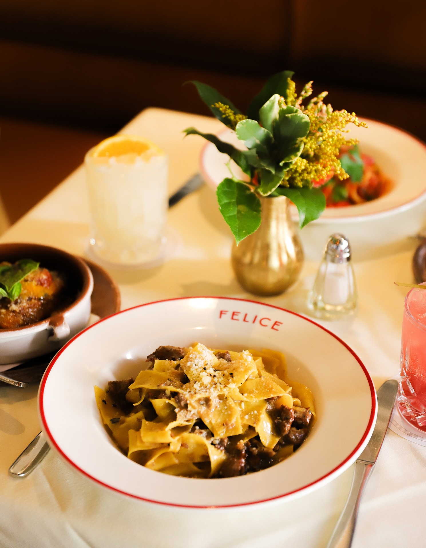 Handmade pappardelle pasta topped with a savory meat sauce and grated parmesan cheese, served on a signature Felice rimmed plate.