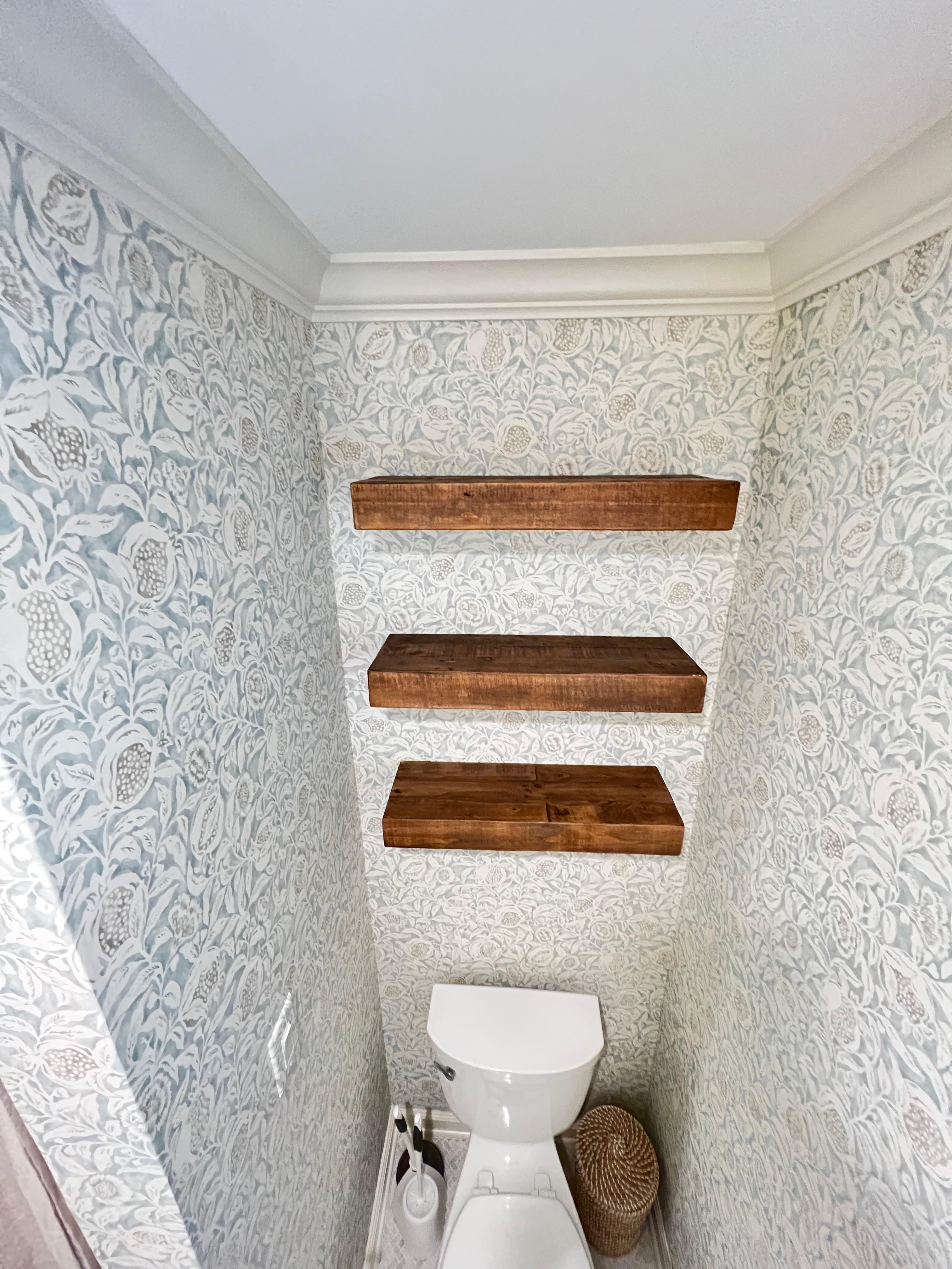 Wood floating shelves mounted above a toilet in a residential bathroom.